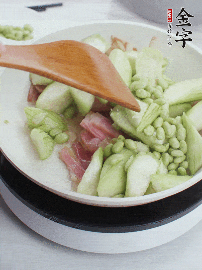 依次下絲瓜、青豆翻炒，炒至絲瓜打蔫縮小。
