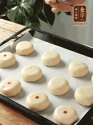 收口向下放在案板上，輕輕將月餅坯按扁，用筷子點紅點做裝飾