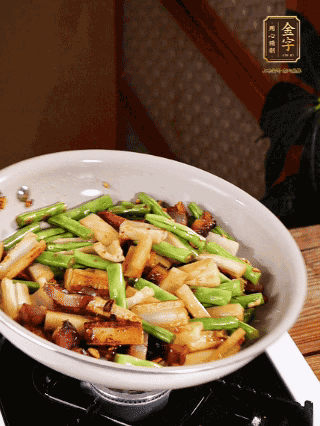 油熱下蒜末、干辣椒、醬肉煸炒出香味，依次下藕條、豆角翻炒均勻